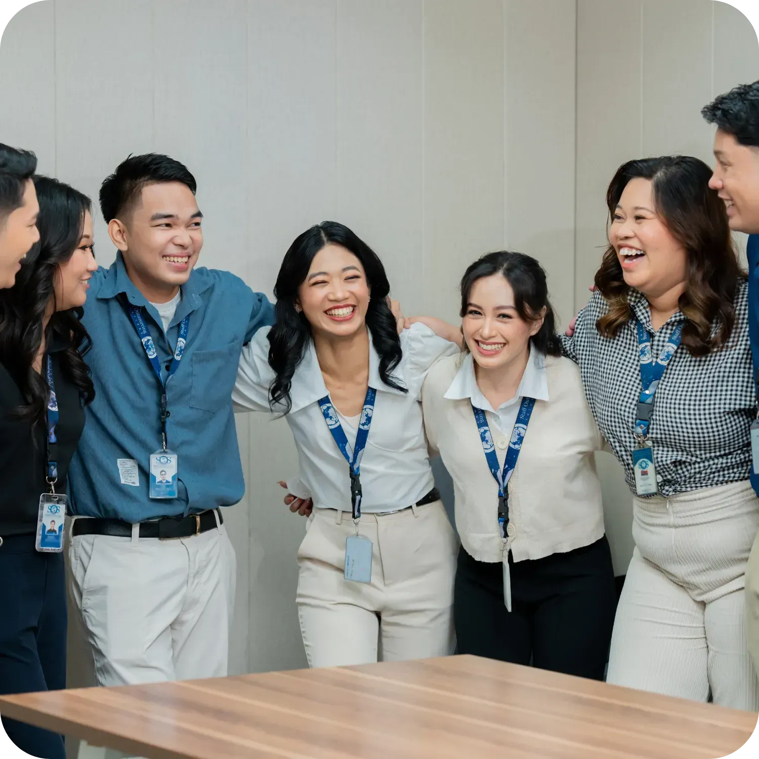 Group of colleagues smiling and embracing in an office.