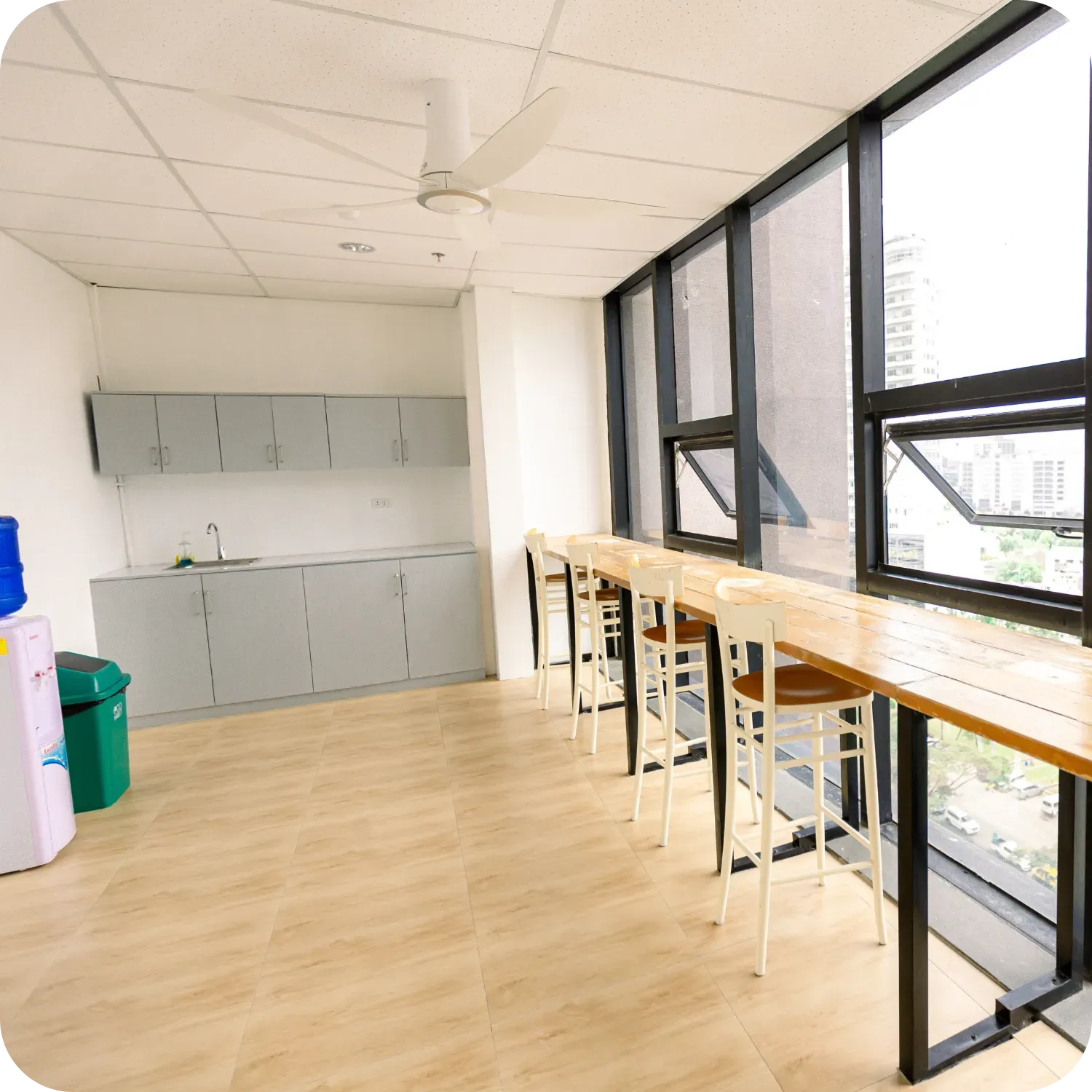 Bright office kitchen with counter seating and large windows.