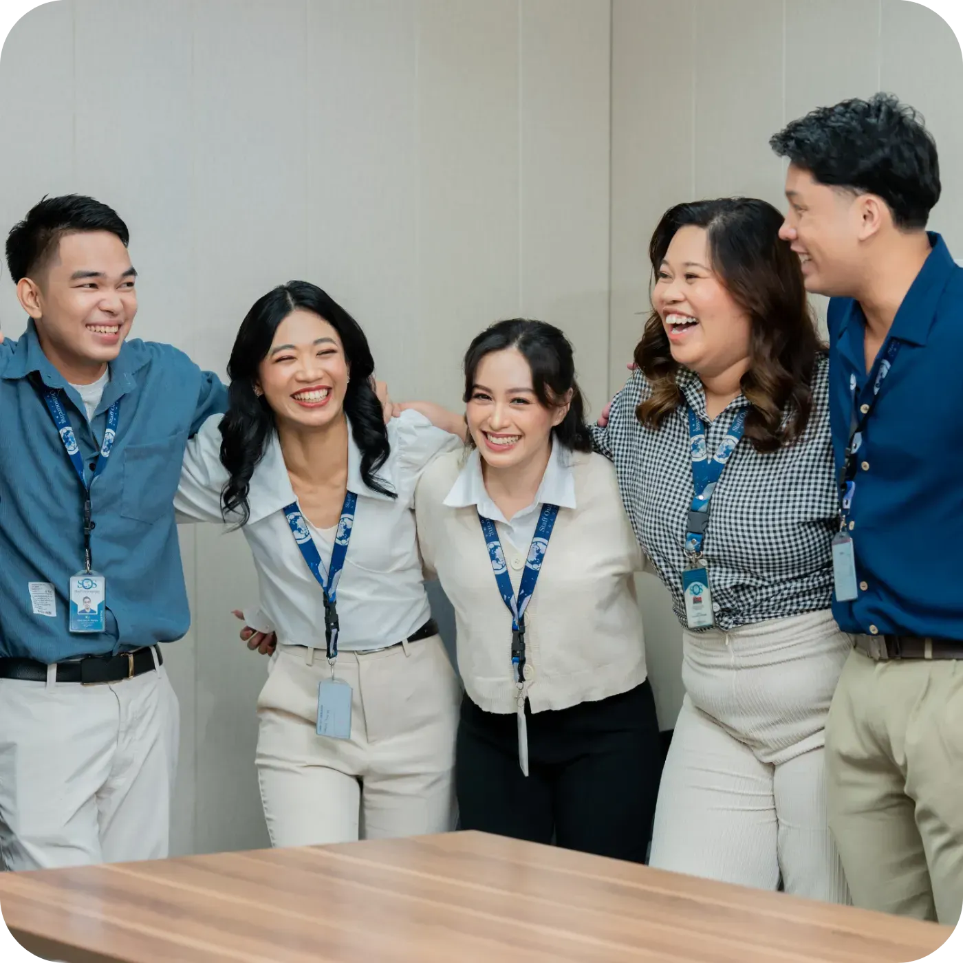 Group of five colleagues smiling and standing in an office setting.